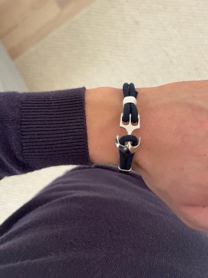 Marint armband med ankare - Snyggt armband med marinblått rep och ett silverfärgat ankare som lås. Armbandet har en cool nautisk stil och detaljer i vitt. Perfekt accessoar för dig som gillar stilrena och trendiga smycken med en twist.
