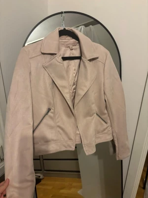 Ljusrosa mocca jacka från Philosophy - Snygg ljusrosa mocca jacka  från Philosophy med klassisk krage och två snedställda dragkedjefickor. Kortare modell som ger en trendig look och passar perfekt till jeans eller klänning. Jackan har en mjuk yta och stilrena detaljer.