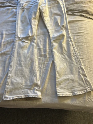 Vita utsvängda jeans med slitningar - Säljer ett par vita jeans från ginatricot storlek S 14+, använt några gånger men är för stora finns lite fläckar men går bort me fläckborttagning