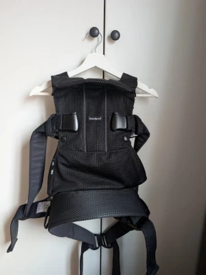 Svart bärsele från BabyBjörn - Säljer en svart bärsele från BabyBjörn i meshmaterial som andas. Selen har breda axelband, justerbara spännen och ergonomisk design för bekväm användning. Passar perfekt för att bära små barn nära kroppen under promenader eller hemma. 0-3 år  3.5–15 kg, 53–100 cm  Fyra bärpositioner  Ergonomisk för dig & ditt barn  Kan justeras för att passa de flesta, från storlek XS till XXL   Ordinarie pris 2899:-  Använt fåtal gånger