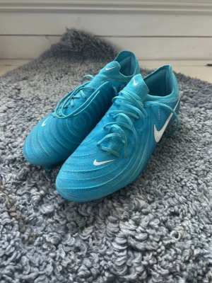 Nike phantom fotbollsskor - Säljer ett par blåa Nike phantom fotbollsskor med vita detaljer och snörning. Säljer pga att de är för små köpte fel storlek och andvända en gång så kunde inte lämna till baks, andvända max 4 gånger så skicket är som nytt🌟ny pris på skorna ligger på 2400 men jag säljer för 1900. Priset är såklart inte ristat i sten så det  kan absolut diskuteras
