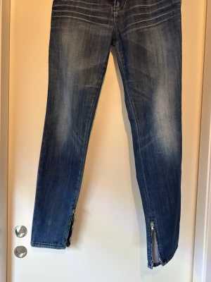 Blå jeans Miss Sixty style J LOT stl 27 - Snygga blå jeans i tvättad denim med dragkedjor vid bensluten och klassiska fem fickor. Jeansen har en smal passform och slitningar för en cool look. Perfekta för dig som gillar en avslappnad men trendig stil. Stl 27. 