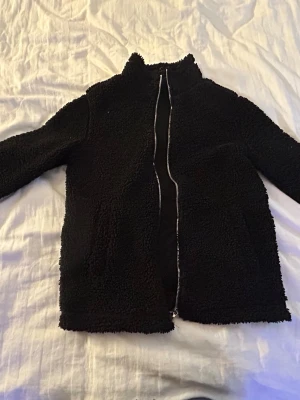 Svart teddyjacka med dragkedja - Mysig svart teddyjacka med hög krage och hel dragkedja framtill. Från hm ganska tunn så funkar perfekt till vår och höst
