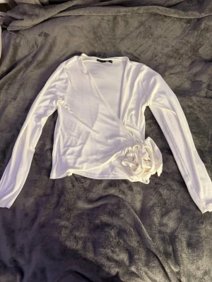 Vit omlottopp med knyt från 157 - Säljer en vit omlottopp från 157 i storlek M. Toppen har långa ärmar och knyt i sidan som ger en snygg och trendig look. Perfekt att styla med jeans eller kjol för en fräsch outfit. Aldrig använd! 