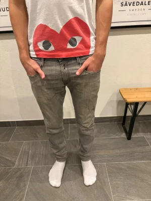 Replay Anbass jeans grå - Säljer ett par gråa slim fit jeans från Replay med klassisk femficksmodell och svarta sömmar. Jeansen har en snygg tvättad look och sitter perfekt i längd/midja. Använda hyfsat mycket men fortfarande i bra skick. Jag är 178 cm och väger 65 kg. 30/30.