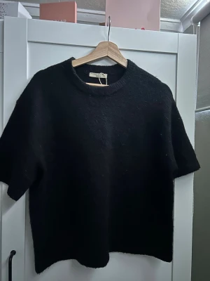Svart stickad topp från Gina Tricot - Säljer en svart stickad topp från Gina Tricot med korta ärmar och rund hals💞