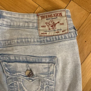 True Religion ljusa jeans - Säljer ett par ljusa blå jeans från True Religion med klassisk femficksdesign och snygga detaljer på bakfickan. Storlek 25! Passar tjejer med stora lår och är super bekväm 💕original pris var 1250kr. Säljer dom för 750kr men kan sänka priset till 700kr 💗