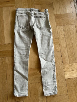 Ljusgrå slim fit jeans - Säljer ett par ljusgrå slim fit jeans med klassisk femficksmodell och normal midja. Jeansen har raka ben och är tillverkade i ett mjukt denimtyg som ger en skön känsla. Perfekta för dig som gillar en clean och stilren look. Från GANT. 170cm