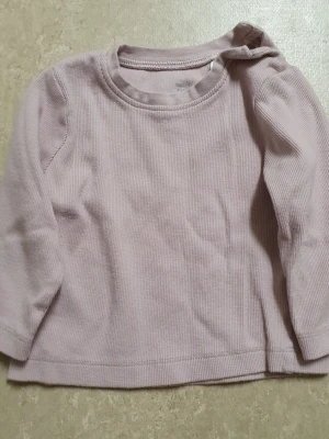 Tröja - En enkel och stilren ljuslila långärmad tröja. Tröjan har rund halsringning och raka ärmar, perfekt för lager på lager.