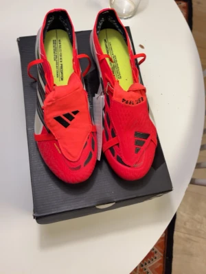Adidas predator Elite - Säljer ett par Adidas Predator fotbollsskor i rött med svarta och vita detaljer. Skorna har låg profil, snörning och täckt plös för bättre bollkontroll. Yttermaterialet är syntet och sulan har dobbar för spel på gräs. Snygg och modern design som sticker ut på planen. Box ingår dessvärre ingen påse som jag tappat bort. Nypris på unisport ligger på 2500kr. Öppet för eventuella byten också.