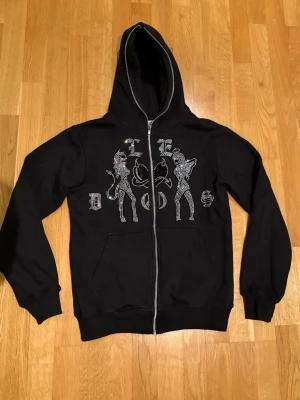 Svart hoodie Le Dos storlek XS - Svart hoodie med dragkedja och huva. Märket är Le Dos och har glittriga detaljer. Storlek  XS