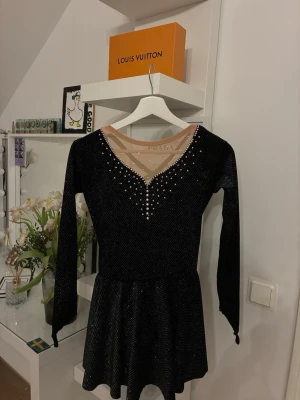 Svart konståkning klänning  - Fin svart konståkningsklänning med glittrande stenar som ger ett elegant och stilrent intryck på isen. ✨⛸️