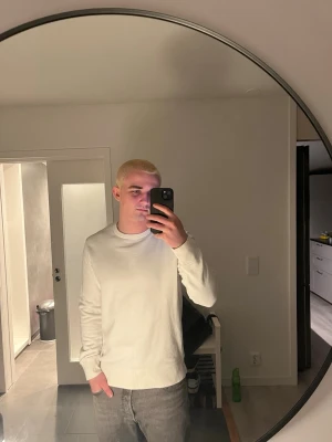 Vit basic sweatshirt - En stilren vit sweatshirt med rund hals och långa ärmar. Tröjan har en enkel och clean design utan tryck eller mönster, perfekt för en avslappnad look. Tillverkad i mjukt material som känns skönt mot huden.