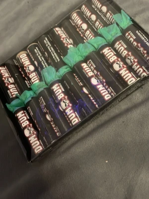 Dum Bum fyrverkeripjäser svart - Säljer ett paket med Dum Bum fyrverkeripjäser i svart färg med vit och röd text. Cylindrisk form och gröna stubiner. Perfekt för dig som gillar pyroteknik och vill ha något extra till firandet.