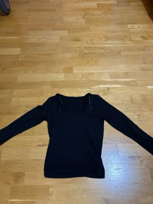 Svart långärmad topp  - En enkel och stilren svart långärmad topp med rund halsringning. Armarna är i slits som man kan se. Storlek M