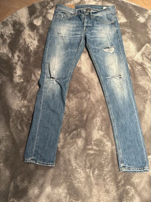 Ljusblå slitna archive jeans - Säljer ett par ljusblå archive  jeans med slitningar och hål på framsidan. Jeansen har klassisk femficksdesign och dragkedja med knapp. Materialet är denim i bomull och passformen är smal hela vägen ner.