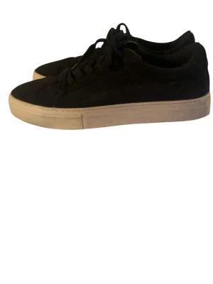 Vagabond Skor - Stilrena svarta sneakers i mocka-look med tjock vit sula och svarta skosnören. Klassisk låg modell som passar till det mesta och ger en clean vibe. Perfekta för dig som gillar minimalistisk stil och vill ha ett par sneakers som funkar året runt.