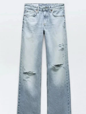 Ljusblå jeans från Zara  - Säljer ett par ljusblå jeans med raka ben och snygga slitningar på både lår och knän. Jeansen har klassisk femficksdesign och är tillverkade i denim. Perfekta för en avslappnad och trendig look.