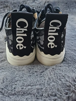 Chloé svarta spets-sneakers - ✨ Original Chloé sneakers – exklusiv modell ✨ Säljer ett par fantastiska Chloé sneakers i svart spets med eleganta läderdetaljer. En väldigt feminin och unik modell som verkligen sticker ut. Endast använda ett fåtal gånger – i mycket fint skick. Väl omhändertagna. Storlek 39 Färg: svart med vit sula Otroligt bekväma och samtidigt stilrena – perfekta både till vardag och mer uppklädda outfits. Ger en lyxig känsla till vilken look som helst. 100% original.