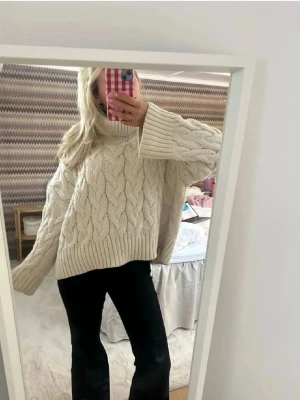 Vit kabelstickad polotröja - Säljer en superfin oversized vit polotröja med grovt kabelstickat mönster. Tröjan har breda, långa ärmar och hög polokrage. Perfekt för dig som gillar en mysig och trendig look under kyliga dagar.