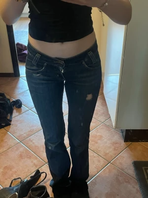 Mörkblå bootcut lowwaist jeans från Lee - Ett par jättesnygga jeans från lee som inte kommer till användning. Slitna längst ner vid foten men inget man tänker på när de är på 