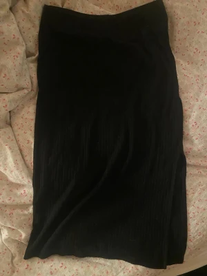 Svart ribbad långkjol - Säljer en svart ribbad långkjol med slits på sidan. Kjolen har en enkel och stilren design som passar till många olika looks. Materialet känns mjukt och stretchigt, vilket gör den bekväm att bära hela dagen. Från Only i storlek M🤍fråga om bild på!