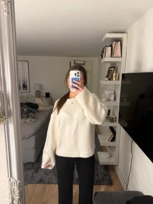 Vit oversized stickad tröja - Mysig vit stickad tröja med oversized passform och långa ärmar. Tröjan har rund halsringning och ribbade muddar vid ärmslut och nederkant. 