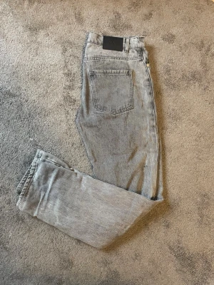 Gråa raka jeans från RYVLS - Säljer ett par gråa raka jeans från RYVLS med klassisk femficksdesign. Jeansen har en tvättad look och är tillverkade i bomull. De är avslappnad/straight i passformen. De är i barnstorlek 170/176. Skulle säga att de passar ungefär 27/28 i midjan och mellan 30/32 i längd