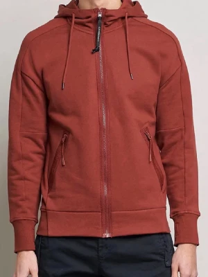 C.P company  - Säljer en snygg rödtfärgad hoodie från C.P. Company med hel dragkedja, två fickor med dragkedja och ikoniska glasögon i huvan. Tillverkad i mjuk bomullsblandning och har justerbar huva med snören. Perfekt för dig som vill sticka ut med en unik detalj.