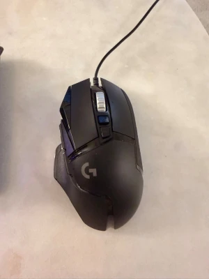 Logitech G502 HERO gamingmus - Säljer en svart Logitech G502 HERO gamingmus med sladd. Musen har flera programmerbara knappar, justerbar vikt och en ergonomisk form som passar perfekt för gaming. Tillverkad i plast med detaljer i metall och gummi för extra grepp.