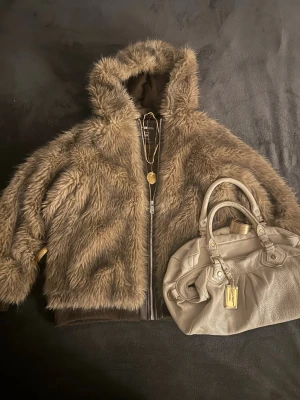 Brun teddyjacka med huva från H&M - Säljer en fluffig brun teddyjacka från H&M med dragkedja framtill och stor huva. Jackan har breda muddar vid ärmslut och nederkant samt två sidofickor. Perfekt för dig som vill ha en mysig och trendig look i höst och vinter. Står XS men sitter som S/M.