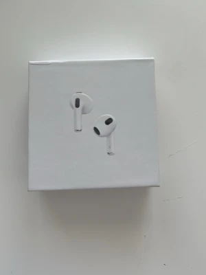 Apple AirPods med MagSafe-laddningsetui - Trådlösa vita in-ear hörlurar från Apple med stilren design och MagSafe-laddningsetui. Perfekta för musik, samtal och smidig anslutning till Apple-enheter. Kompakt och lätt form i plast med klassisk Apple-look.
