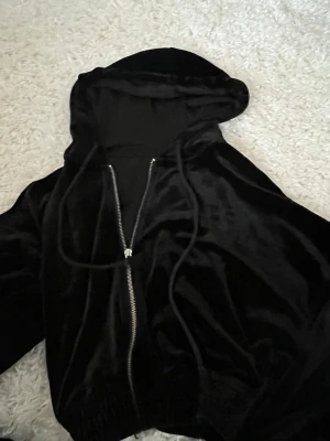 Svart velour hoodie med dragkedja - Snygg svart hoodie i mjuk velour från Gina Tricot. Tröjan har dragkedja framtill, huva med snören och ribbade muddar. Perfekt för en chill och trendig look.