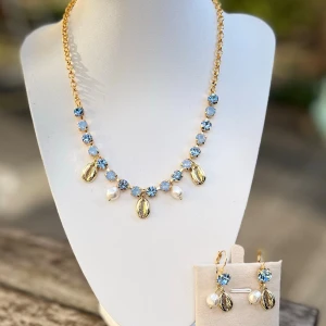 Smyckesset halsband örhängen charms kristaller  - Halsband och örhängen med brisyrkrok i guldpläterad mässing med kristaller, Pärlor och charms. Färg Light Sapphire och Light Sapphire Opal. Pärlor i Pearl. Ss29 6mm. Längd 51cm inkl lås. Finns även att få i andra färger på kristallerna. Sista bilderna visar andra varianter.  Jag skickar endast spårbart, samfraktar. Fast pris. Besök gärna mina övriga annonser.  Till mina smycken använder jag kristaller från Preciosa, Aurora och Swarowski.