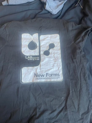 Svart New Forms t-shirt med tryck - Cool svart t-shirt från New Forms med stort grafiskt tryck och texten 'LABsounds' och 'New Forms Underground Concept' på ryggen. Mindre logga framtill. Klassisk passform och korta ärmar, perfekt till jeans eller shorts. Kontakta gärna ❤️