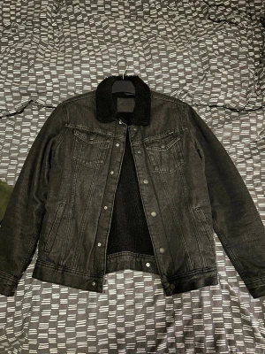 Svart jeansjacka med teddykrage - Snygg svart jeansjacka från Jack & Jones med mjuk teddykrage och teddyfoder. Klassisk modell med två bröstfickor med lock och knappar samt sidofickor. Perfekt för dig som vill ha en stilren och trendig look med extra värme. Knappt använd. Storlek xs men passar även s.