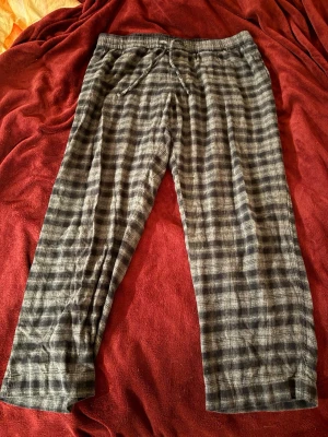 Rutiga pyjamasbyxor från H&M XL - Mysiga pyjamasbyxor från H&M i storlek XL. Byxorna är grå med svart rutmönster och har resår i midjan samt dragsko för extra komfort. Perfekta för chillkvällar hemma eller när du vill ha det extra bekvämt.