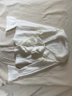 Vit fluffig kofta från NA-KD - Supermjuk och fluffig vit kofta från NA-KD med volangkant och knytning framtill. 