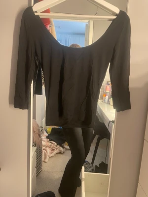Svart offshoulder topp med trekvartsärm - Snygg svart offshoulder topp med trekvartsärm och bred urringning. Perfekt att styla med jeans eller kjol för en trendig look. Materialet känns mjukt och stretchigt, vilket gör toppen bekväm att bära hela dagen.