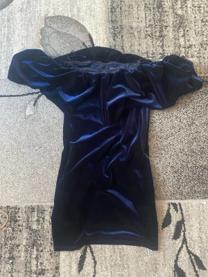 Gina tricot Mörkblå sammetsklänning offshoulder - Supersnygg mörkblå sammetsklänning med offshoulder-modell och kort längd. Klänning är typ tajt den anpassar sig för din kropp, har endast använt den 3 gånger, super söt passar för balen eller festklänningar för fler bilder fråga