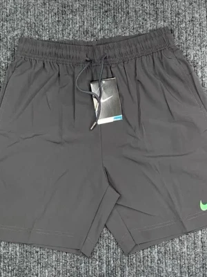 Svarta Nike shorts med snörning - Svarta shorts från Nike med elastisk midja och snörning framtill. Liten grön Nike-logga på ena benet. Perfekta för träning eller chill. Tillverkade i ett lätt och syntetiskt material som andas.
