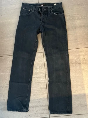 Svarta jeans från Nudie - Säljer ett par svarta slim fit jeans från Nudie Jeans. Klassisk femficksmodell med dragkedja och knapp, samt tydliga sömmar. Inte använda mycket. 