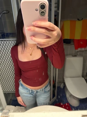 Vinröd långärmad topp - Säljer en vinröd långärmad topp från Amisu med fyrkantig ringning och tight passform. Toppen är croppad och har en stilren design som passar perfekt till jeans eller kjol. Materialet är mjukt och stretchigt för en bekväm känsla. Den är lite nopprig på vissa ställen men de är inget man märker av om man inte kollar noggrant🙌