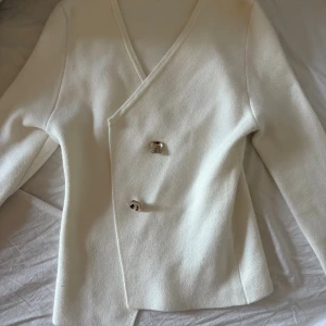 Vit omlottkofta med stora knappar - Säljer en trendig vit omlottkofta med guldknappar. Koftan har lång ärm och en stilren, något figurnära passform💕💕💕💕