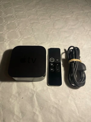 Apple TV HD 32 GB A 1625  med fjärrkontroll och sladd - Apple TV HD 32 GB modell A1625 mediaspelare i svart med tillhörande svart fjärrkontroll och strömkabel. Enheten har en stilren, fyrkantig design med rundade hörn och Apple-logga på ovansidan. Perfekt för streaming och appar direkt till din TV. Går att ladda ner appar. För frågor är det bara att skriva. Postar inom 1-2 dagar. 
