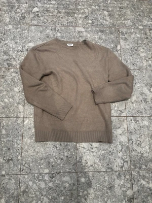Beige tröja från Kappahl - Säljer en stilren beige tröja från Kappahl i storlek 170. Tröjan har rund halsringning, långa ärmar och ribbade muddar vid ärmslut och nederkant. Perfekt för en enkel och clean look.