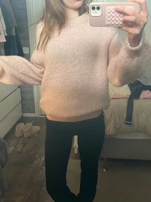 Ljusrosa oversized stickad tröja - Mysig ljusrosa stickad tröja med oversized passform och breda ärmar. Tröjan har rund halsringning och är gjord i ett fluffigt, mjukt material som känns skönt mot huden. Perfekt för att hålla värmen under kyliga dagar. Knappt använd!