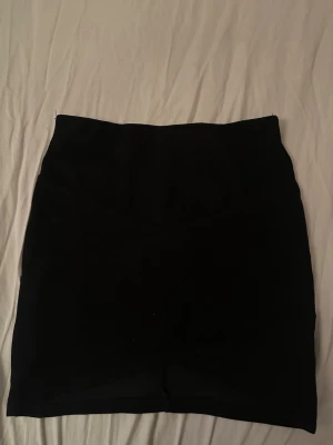 Svart kortkjol från Cubus - Passar till xs/s. Enkel och stilren svart kortkjol från Cubus. Kjolen har en rak passform och är tillverkad i ett mjukt material som känns bekvämt. Perfekt att matcha med en crop top eller hoodie för en chill look.