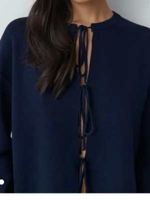 Mörkblå långärmad tröja med knyten - Mörkblå långärmad tröja från Gina Tricot med tre knytband framtill. Tröjan har rund halsringning, långa ärmar. Använd fåtal gånger.