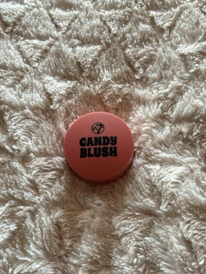 W7 Candy Blush Classic Rouge - Söt rouge från W7 i färgen Classic. Kommer i en rund, kompakt dosa i rosa plast med svart text. Perfekt för att ge kinderna en fräsch och naturlig ton. Enkel att ta med i väskan och smidig att applicera.